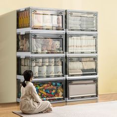 a woman sitting on the floor in front of a stack of drawers