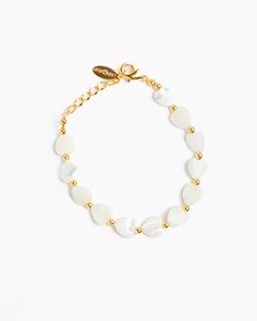 a white bracelet with gold beads and a leaf charm on the clasp, against a white background