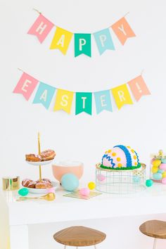 a table topped with cakes and donuts next to bunting flags that say happy easter