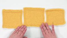 two hands are shown holding the edge of a pair of yellow knitted mitts