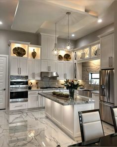 a large kitchen with white cabinets and marble counter tops, stainless steel appliances and an island