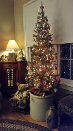 a decorated christmas tree in a living room next to a window with lights on it