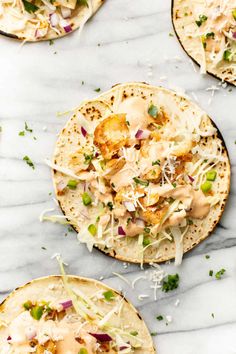 three tortillas topped with shredded cheese and toppings on a marble counter top