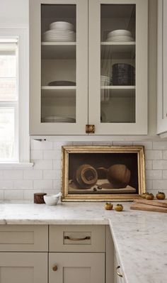 a kitchen with white cabinets and marble counter tops in front of an open cabinet door