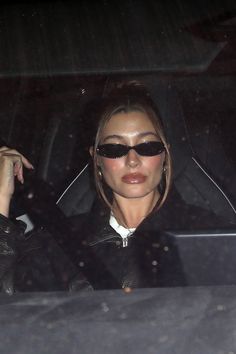 a woman wearing sunglasses is sitting in the back seat of a car