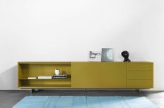 a yellow entertainment center with books and magazines on the top, in a white room