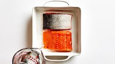 two raw salmons are sitting on a white plate next to a can of coke