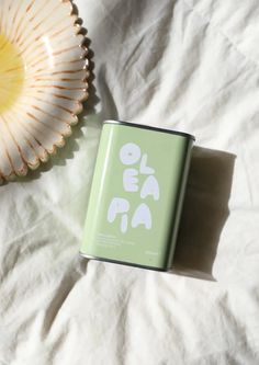 a can of tea sitting on top of a bed next to a bowl and plate