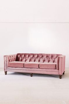 a pink couch sitting on top of a white floor next to a wall in an empty room