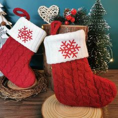 two red and white knitted stockings with snowflakes on them next to a christmas tree