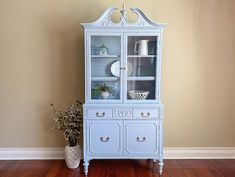 a white china cabinet sitting on top of a hard wood floor next to a wall