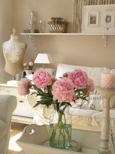 pink carnations in a vase on a coffee table next to a white couch