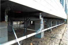 pipes are attached to the side of a building under construction, with sand surrounding them