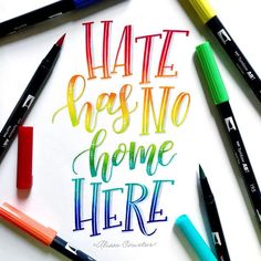 some crayons and markers are laying on top of a piece of paper that says hate goes no home here