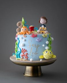 a blue cake with sea life on it and a little boy in the top tier