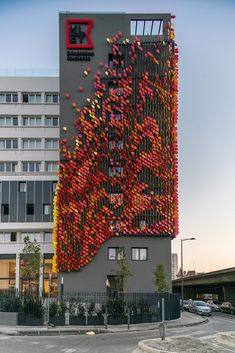 a large building with lots of red and yellow objects on it's side in front of a parking lot