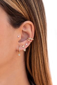 a woman wearing gold ear cuffs with white stones