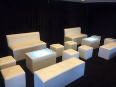 a group of white chairs and stools sitting on top of a black floor