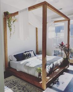 a bed sitting in the middle of a bedroom next to a window with plants on it