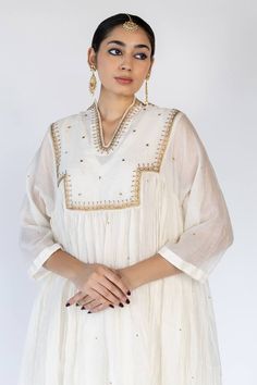 Ivory flared kurta with thread floral embroidered motifs and sequin embellishments on yoke. Comes with an inner and matching pant.
Components: 3
Pattern: Embroidered
Type Of Work: Thread, Sequin
Neckline: V-neck
Sleeve Type: Three quarter
Fabric: Chanderi Cotton, Lining: Cotton
Color: Ivory
Other Details: 
Flared silhouette
Note: Dupatta worn by the model is not for sale
Occasion: Sangeet,Mehendi and Haldi - Aza Fashions Traditional V-neck Embroidered Top For Wedding, Traditional Embroidered V-neck Top For Wedding, White Anarkali Embroidered Festive Dress, White Anarkali Embroidered Dress For Festive Occasions, Elegant Festive Top With Chikankari Embroidery, Elegant White Embroidered Dress For Festivals, Traditional White Chikankari Embroidered Top, Traditional Resham Embroidered V-neck Top, Anarkali Style White Kaftan For Festivals