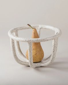 a pear in a bowl made out of white plastic with an interlocked design