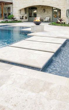 an outdoor pool with steps leading to it and a fire pit in the middle next to it