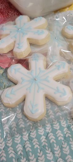 several decorated cookies in plastic wrappers on top of a blue and white table cloth