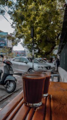 a cup of coffee sitting on top of a wooden table next to a scooter