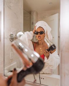 a woman is drying her hair in the bathroom mirror while holding a blow dryer