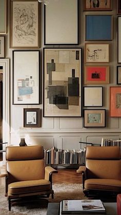 a living room filled with lots of framed pictures on the wall above two couches