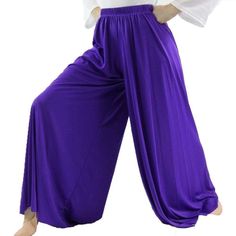 a woman in purple pants and white shirt posing for the camera with her hands on her hips