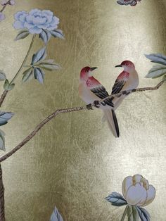 two birds are sitting on a branch with flowers and leaves painted on the wall behind them