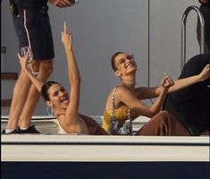 three people sitting on the back of a boat with their arms up in the air