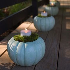 three white pumpkin shaped candles sitting on top of a wooden table