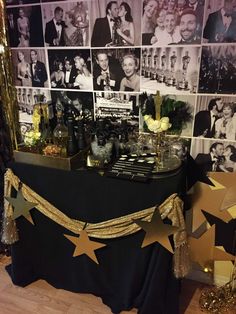 a black table topped with gold stars next to a wall covered in pictures and photos