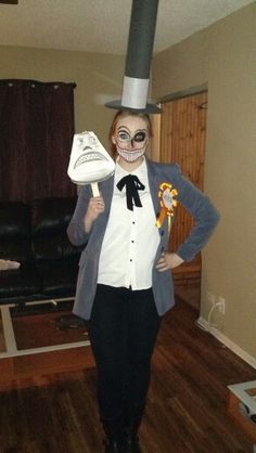 a woman wearing a top hat and skeleton face paint holding a shoe in her hands