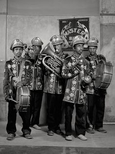 a group of men standing next to each other with musical instruments in their hands and helmets on