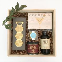 a wooden box with some bottles and labels in it on a white surface next to a plant