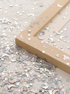 a wooden frame sitting on top of a table covered in stars and moon confetti