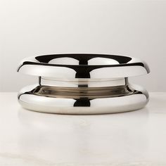 a silver plate sitting on top of a white counter next to a black and white bowl