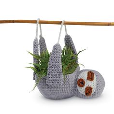 a crocheted sloth hanging from a clothes line next to a planter