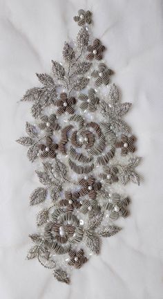 a christmas tree made out of silver ornaments on a white sheet with snowflakes