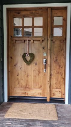 a wooden door with a heart hanging on it's side and a rug in front of it