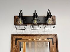 three light fixtures mounted on the wall above a mirror