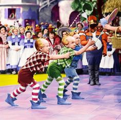 two children are dancing in front of an audience with clowns on the sidelines