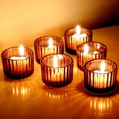 five lit candles sitting on top of a wooden table