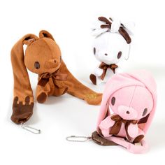 three stuffed animals sitting next to each other on a white surface and one is wearing a pink hoodie