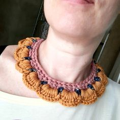 a close up of a person wearing a crocheted necklace