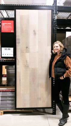 a woman standing next to a large wooden panel