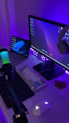 a computer desk with a keyboard, mouse and headphones next to a laptop on it